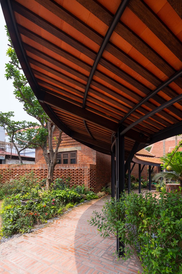Hành lang giữa sân nhà có mái vòm oval tạo cảm giác gần gũi như đường làng cổ yên bình. Thiết kế này giúp công trình có thể đón ánh sáng tự nhiên, thông gió và tăng tính kết nối giữa các khu vực trong nhà.