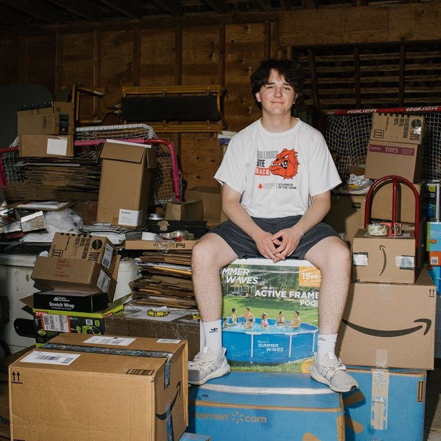 Max Hayden, 16 tuổi ngồi b&ecirc;n những đơn h&agrave;ng đang chuẩn bị được vận chuyển trong garage của gia đ&igrave;nh. Ảnh: WSJ