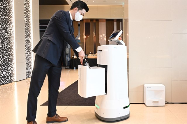Robot CLOi ServeBot của LG Electronics giao c&aacute;c chai rượu cho một nh&acirc;n vi&ecirc;n kh&aacute;ch sạn